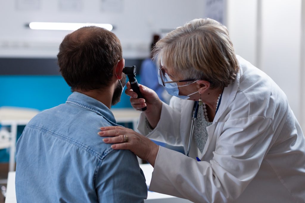 close up of physician using otoscope to do ear consultation with patient