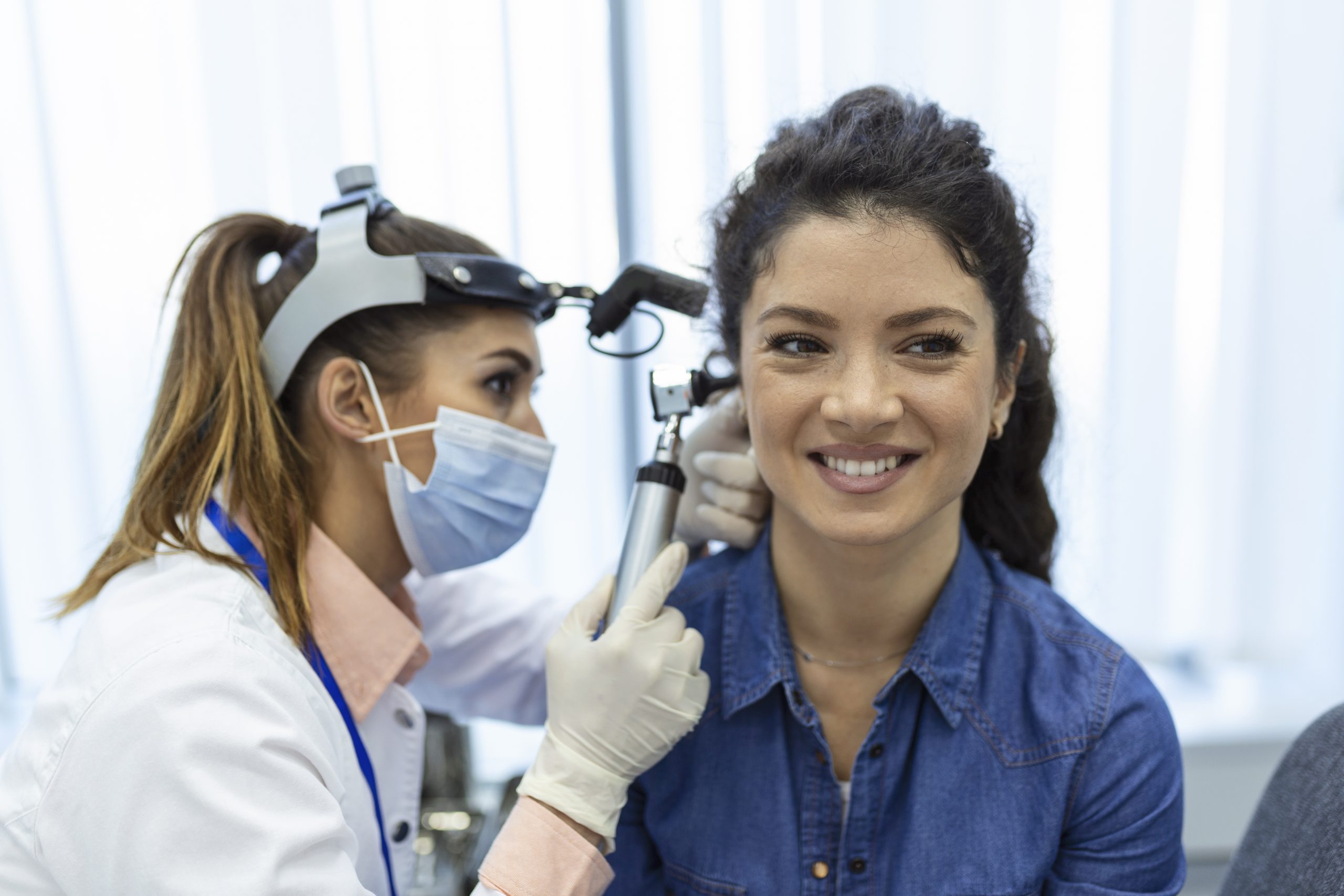 hearing exam. otolaryngologist doctor checking woman's ear using otoscope or auriscope at medical clinic.